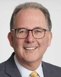 Alister in a suit, smiling.